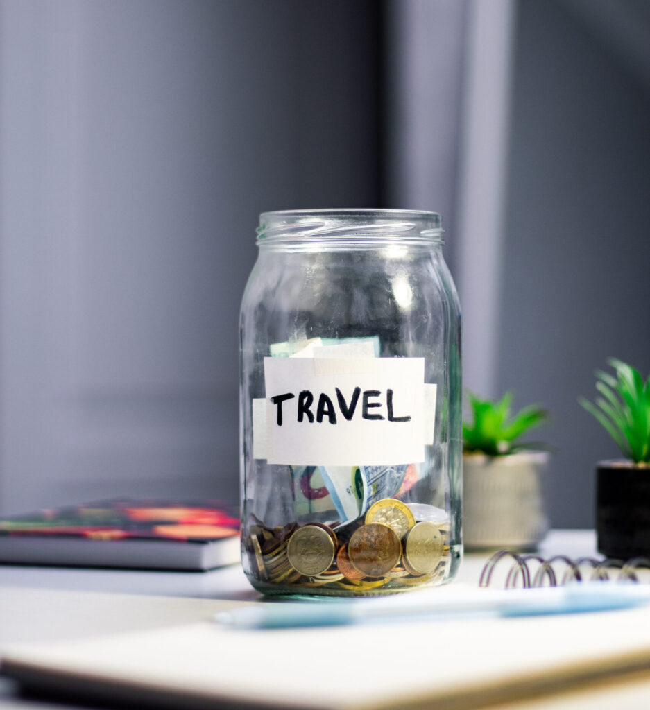 Travel savings in jar. Money being added to travel themed savings container. Inspires adventure planning and purposeful financial habits